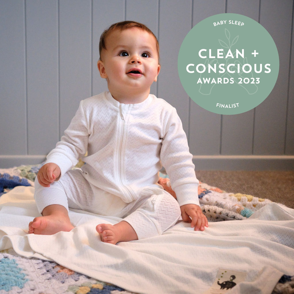 Baby wearing organic cotton growsuit and blanket