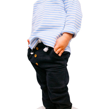 Child wearing a blue and white striped shirt and black pants on a white background