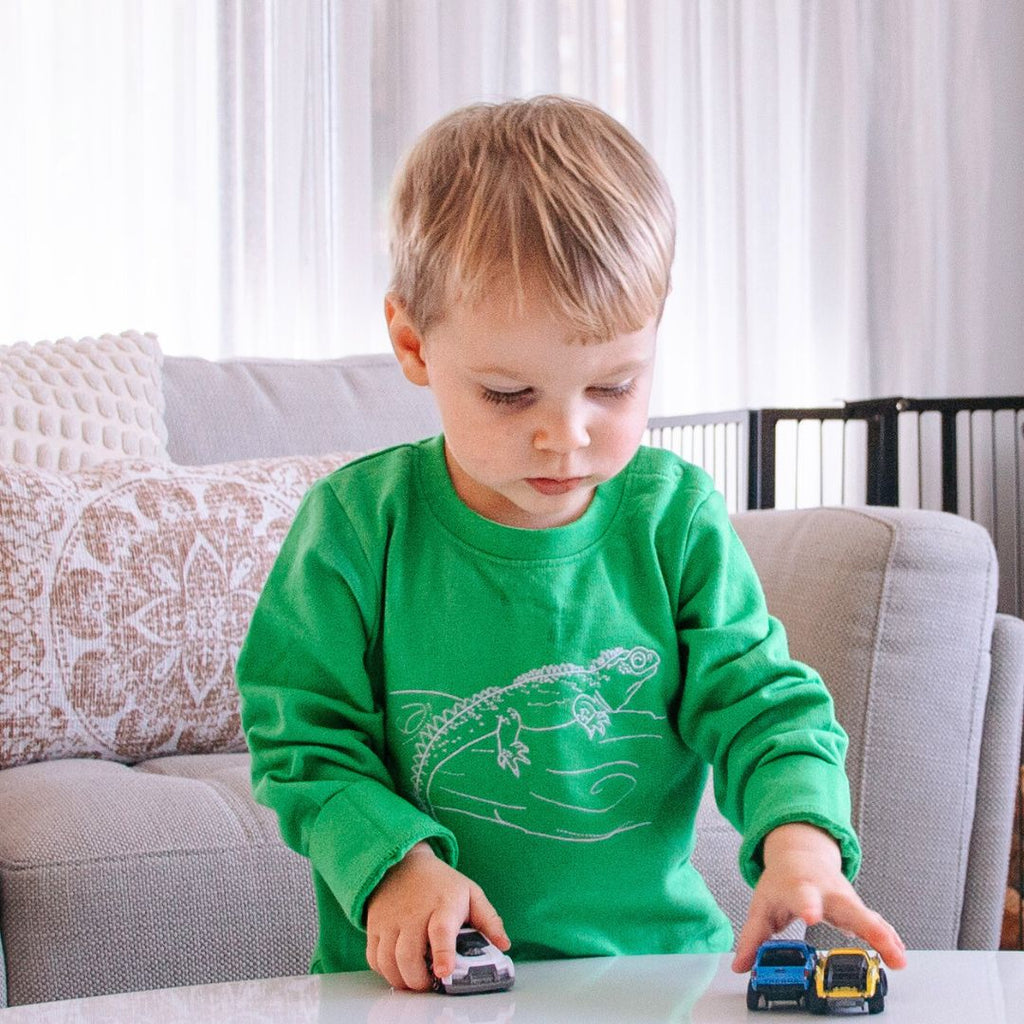 Child playing with toy cars on a table in a living room.