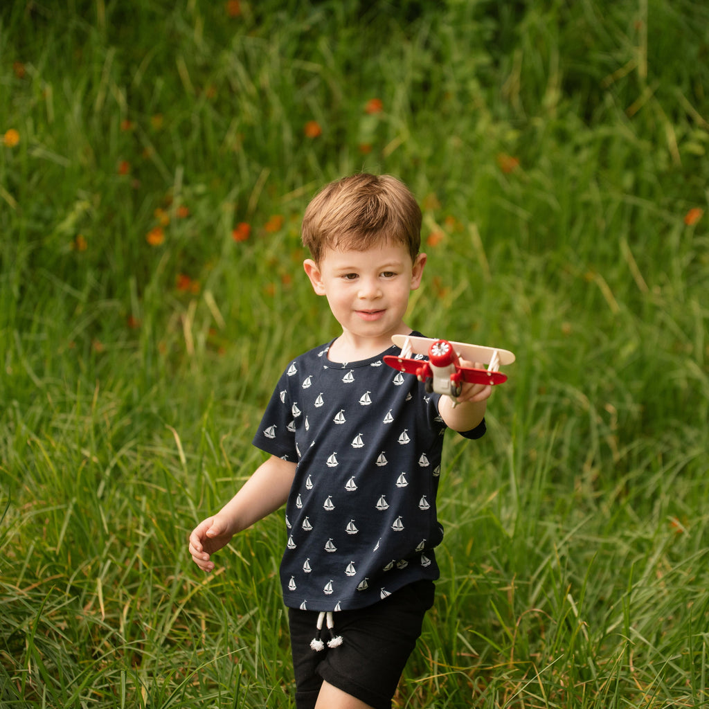 Child holding a toy airplane in a grassy field