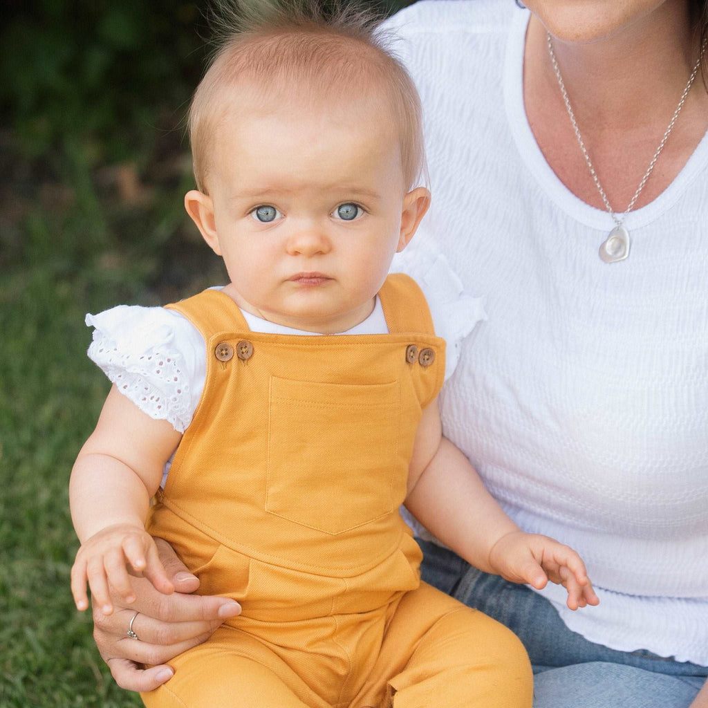 Child wearing Organic Cotton Broderie Angel Top and mustard dungarees