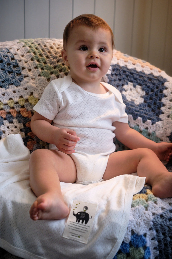 baby wearing organic cotton bodysuit and blanket
