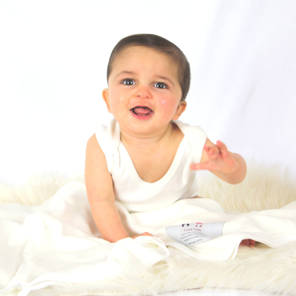 Baby wearing natural organic cotton singlet and swaddle blanket